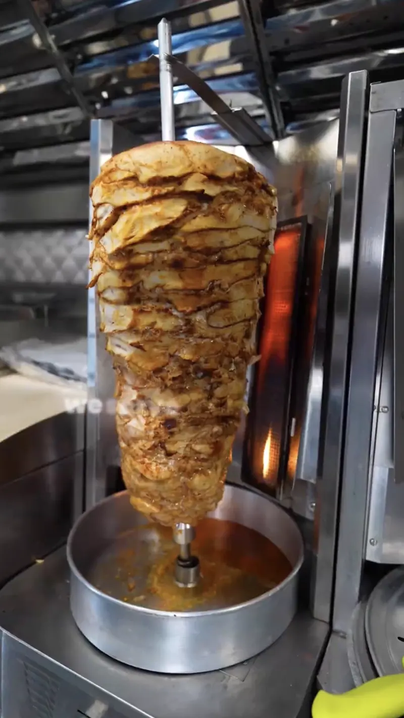The red Shawerma G food truck with yellow lettering and Flavor That Rolls painted on the side